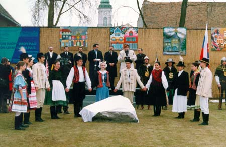 lenovia folklrneho sboru Dunaj obleen v tradinch slovenskch a maarskch krojoch - okolo zkladnho kamea stavby.